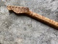 Bird eye maple guitar neck on old grey concrete.