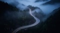 A bird eye scenery view of a winding road cutting turns through clouds of serpentine a dense forest , mountain landscape.Top Down Royalty Free Stock Photo