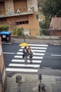 Bird-eye view of a young couple in love is chatting while crossing crosswalk during a rainy day. Walk, rain, city, relationship