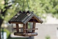 Bird feeder hang on the tree in the garden. Wooden bird house in daytime. Bokeh background. Copy space Royalty Free Stock Photo