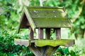 Bird feeder house shaped garden accessory weathered covered in moss Royalty Free Stock Photo