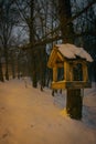 Bird feeder in snowy forest. Wooden bird house in winter park. Animal care concept. Handmade bird feeder in snow on tree Royalty Free Stock Photo