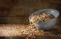 Bird food for winter feeding, mixed seeds like sunflower, corn, millet and more are falling out of a bowl on a rustic wooden board Royalty Free Stock Photo