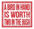 A BIRD IN HAND IS WORTH TWO IN THE BUSH, text on red grungy stamp sign Royalty Free Stock Photo