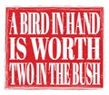 A BIRD IN HAND IS WORTH TWO IN THE BUSH, text on red stamp sign Royalty Free Stock Photo