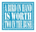 A BIRD IN HAND IS WORTH TWO IN THE BUSH, text written on blue stamp sign Royalty Free Stock Photo