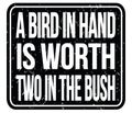 A BIRD IN HAND IS WORTH TWO IN THE BUSH, words on black stamp sign Royalty Free Stock Photo