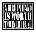 A BIRD IN HAND IS WORTH TWO IN THE BUSH, text written on black stamp sign Royalty Free Stock Photo