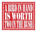 A BIRD IN HAND IS WORTH TWO IN THE BUSH, text written on red stamp sign Royalty Free Stock Photo
