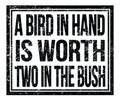 A BIRD IN HAND IS WORTH TWO IN THE BUSH, text on black grungy stamp sign Royalty Free Stock Photo