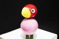 Bird made of wood, carved figure close-up. Black background with pink bird and red wood head Royalty Free Stock Photo