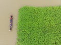 Bird\'s eye view of a narrow wooden boat full of people sailing in a dirty river