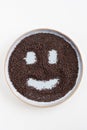 Bird\'s eye view of a plate with black mustard seeds with a smiley face