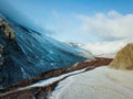 A bird\'s eye view of a ridgeline half-covered with snow in a forest with a sunburst in the upper left corner of the frame. Royalty Free Stock Photo