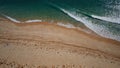 bird\'s-eye view of seashore, blue waters break with white foam in waves on an empty sandy beach Royalty Free Stock Photo