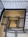 Bird\'s-eye view from top to bottom of stairwell in tall block of flats with banisters Royalty Free Stock Photo