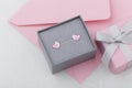 Bird shape with heart earring studs in gray gift box on pink envelope background