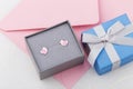 Bird shape with heart earring studs in gray gift box on pink envelope background