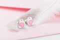 Bird shape with heart earring studs on pink background with feat