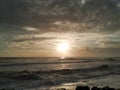 Bird in silhouette flying over beach at sunset with dramatic, moody clouds Royalty Free Stock Photo