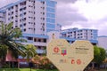 Bird standing on heart signage at Nee Soon Central on bright sunny day. HDB flats in background Royalty Free Stock Photo