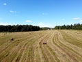 Bird view to rural summer field with many rolled haystacks and the forest on skyline on bright sunny day under blue cloudless sky Royalty Free Stock Photo