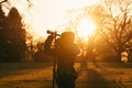 bird watcher in a park at sundown, telescope in hand