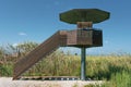 Bird watcher tower in Ebro Delta wetland area with rice field against a cloudy blue sky. Empty copy space