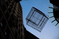 Birdcage hanging over the street against blue sky in dark shadow.