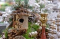 Birdhouse with gold sequins in a Christmas composition with cones and a candlestick.