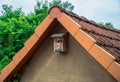 Birdhouse hanging on the wall of the house under the tiled roof