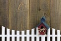 Birdhouse hanging on white picket fence