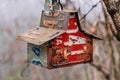 Birdhouse made with various old license plates hanging from a tree