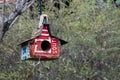 Birdhouse made with various old license plates hanging from a tree