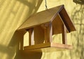 Birdhouse made of wood on a background of a yellow wall of a house.