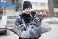 Birds doves eat sunflower seeds from the hands of a beautiful young girl in a black jacket