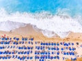 Birds eye view of a beach with big waves, sunbeds and umbrellas