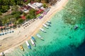 Birds eye view of colorful sun umbrellas and boats on a small, warm tropical beach