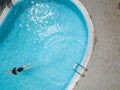 Birds eye view of an outdoor pool and a long hair black swimsuit girl swims in the water Royalty Free Stock Photo