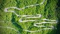 Birds eye view shot of a long twisted road surrounded by trees