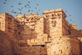 Birds flying over the towers of historical Jaisalmer fort with monumental stone walls in old city of Rajasthan, India Royalty Free Stock Photo