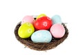 Birds nest filled with colorful, painted Easter eggs isolated on a white background