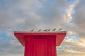 Birds Perched on a Red Beach Hut