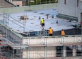 Birdseye view of roofer waterproofing the flat roof of a commercial building.