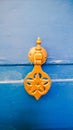 Bright yellow brass knocker on a vibrant blue door, Morocco