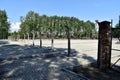 A distant view of the International Memorial taken through the remains of an electrified fence at the Birkenau Concentration Camp