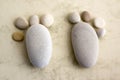 Two tiny stone feet and ten toes on beige background, stone in the shape of a human feet Royalty Free Stock Photo