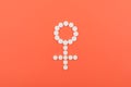 Birth Control Pills, Oral Contraceptive, Hormonal Method. White pills in the form of female Venus symbol on coral background.