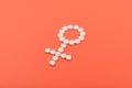 Birth Control Pills, Oral Contraceptive, Hormonal Method. White pills in the form of female Venus symbol on coral background.