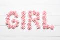 Birth of girl, word made of pink roses on white wooden table con